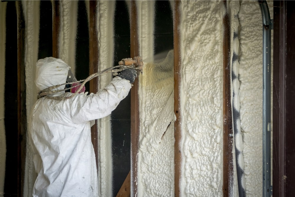 man applying spray foam insulation to walls