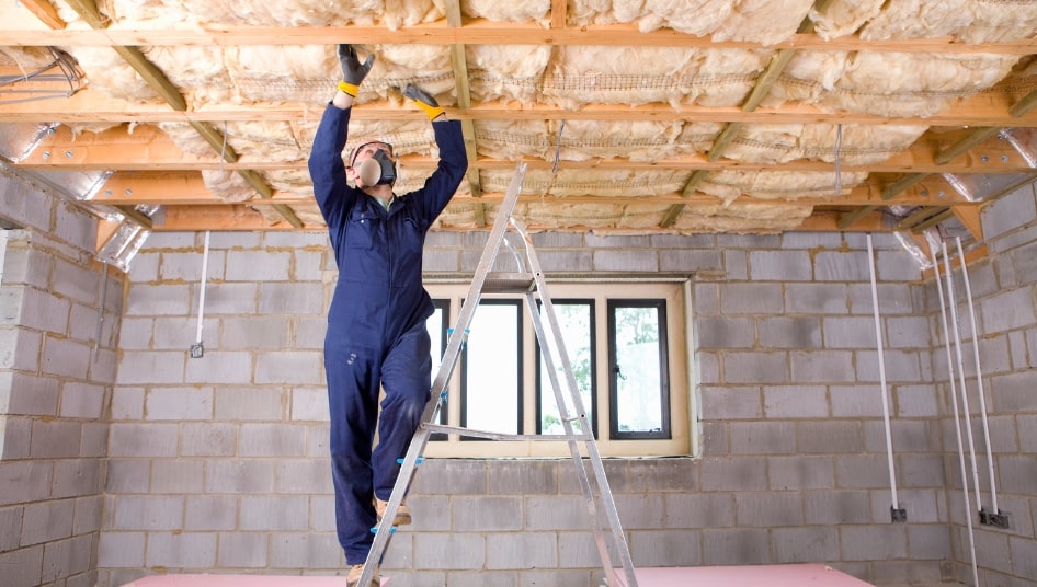 man installing insulation in basement ceiling