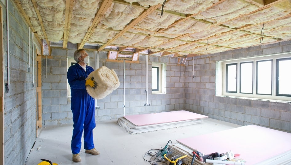 man installing insulation in an empty basement